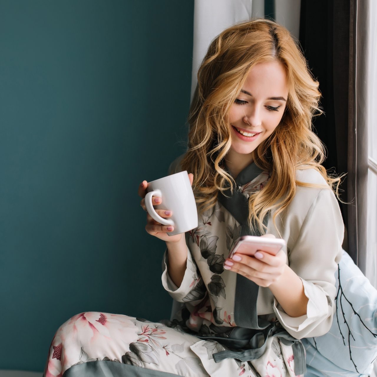 http://ecaterinamoga.com/wp-content/uploads/2021/04/pretty-blonde-girl-sitting-window-sill-with-cup-coffee-tea-smartphone-hands-she-has-long-blonde-wavy-hair-smile-looking-her-phone-wearing-beautiful-silk-pajama-1280x1280.jpg